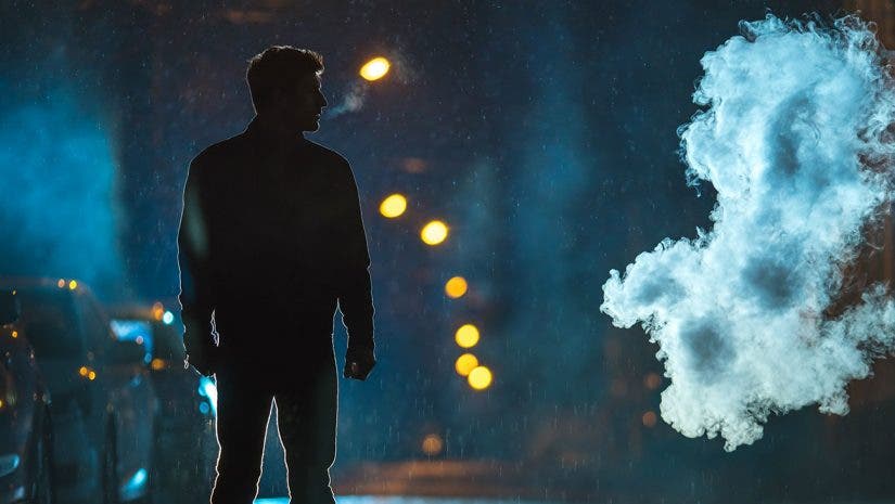 man standing in the street under the rain during night time