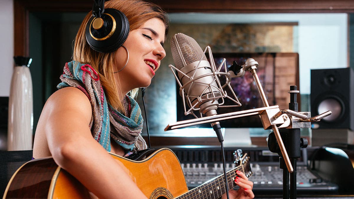 girl singing with guitar recording studio
