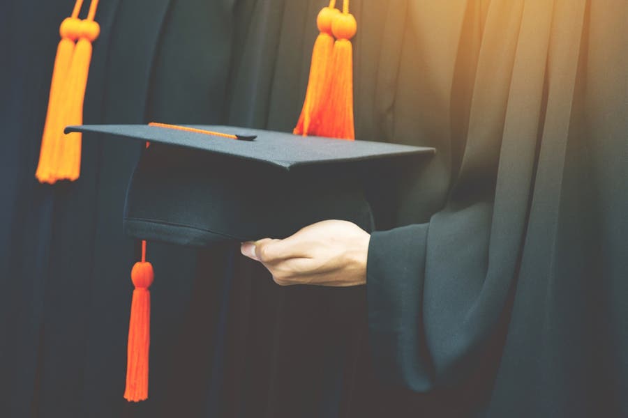 Student hold hats in hand during commencement