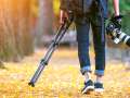 Professional photographer with camera and tripod in autumn.