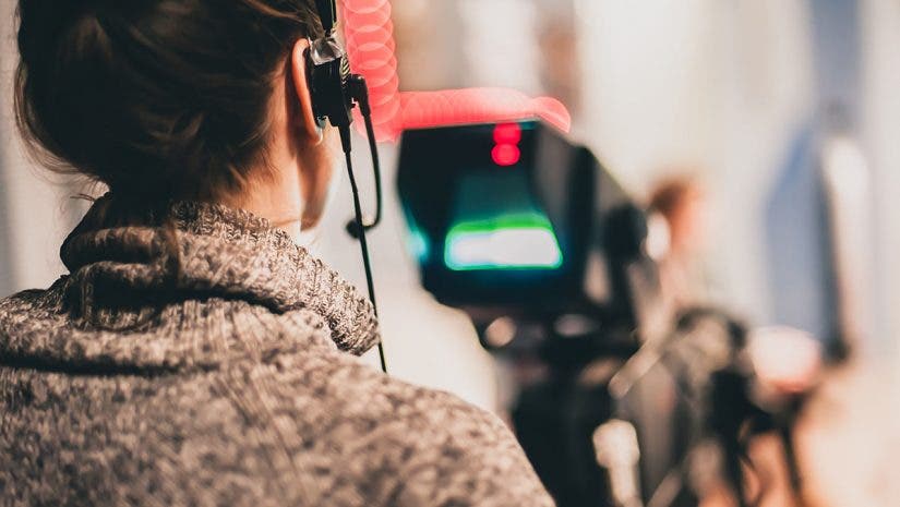 documentary filmmaker recording footage and audio with camera and headphones