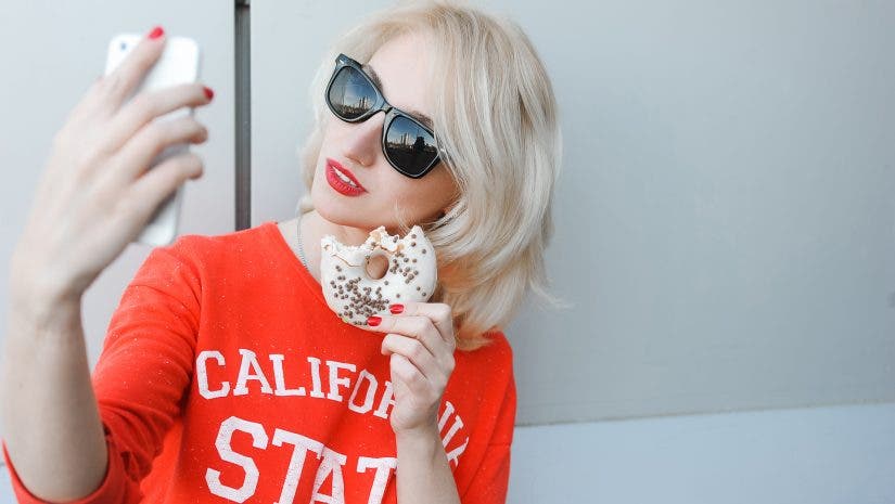 girl eating donut and taking a selfie