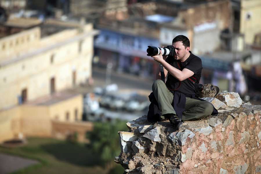 photographer sitting on a rock overlooking the city