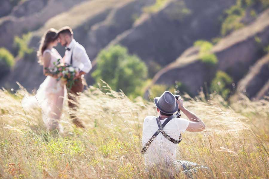 man taking wedding photos of couple outdoors