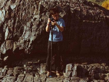 photographer with camera monopod on rocks
