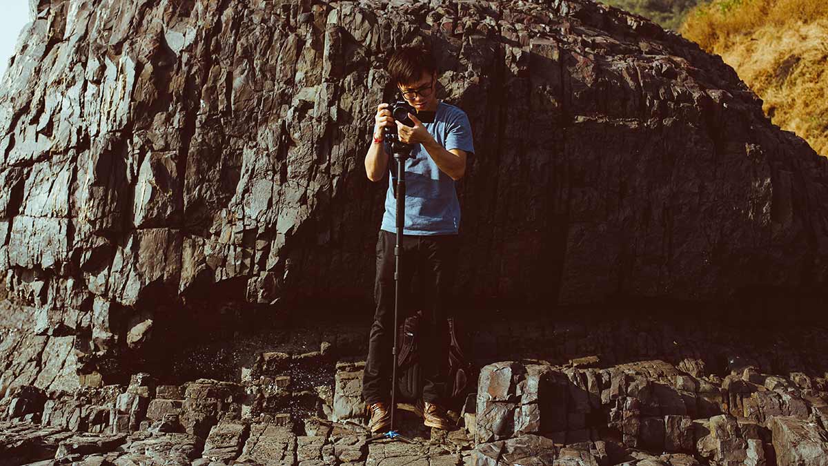 photographer with camera monopod on rocks
