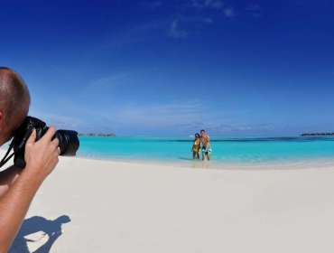 beach photographer takes picture of couple wading in water