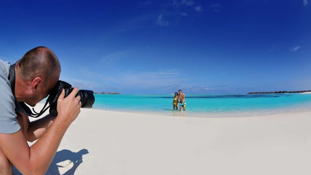 beach photographer takes picture of couple wading in water