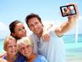 young family takes selfie on the beach