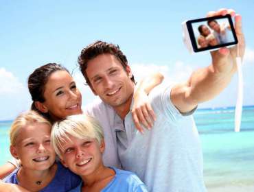 young family takes selfie on the beach