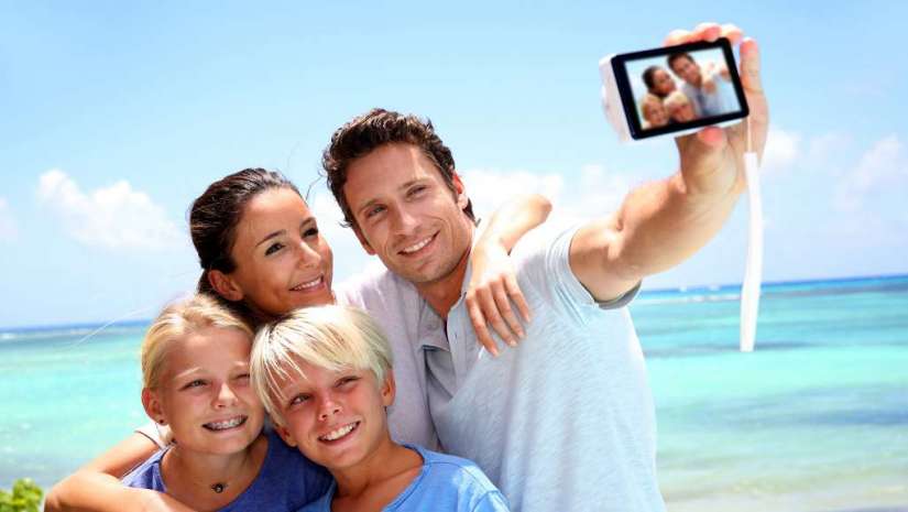 young family takes selfie on the beach
