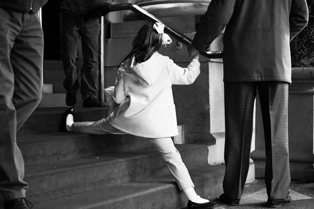 little girl performing a split on stairs street photography