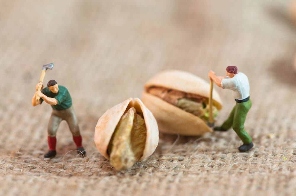 Macro shot of miniature human figures with pistachio nuts