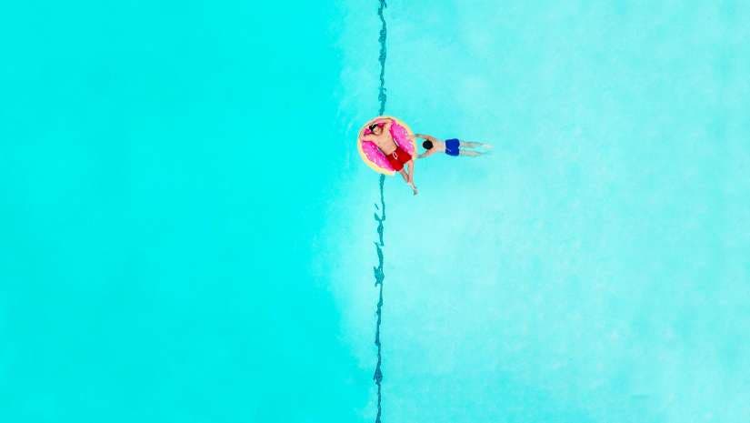 two men relaxing on donut pool floatie drone photography