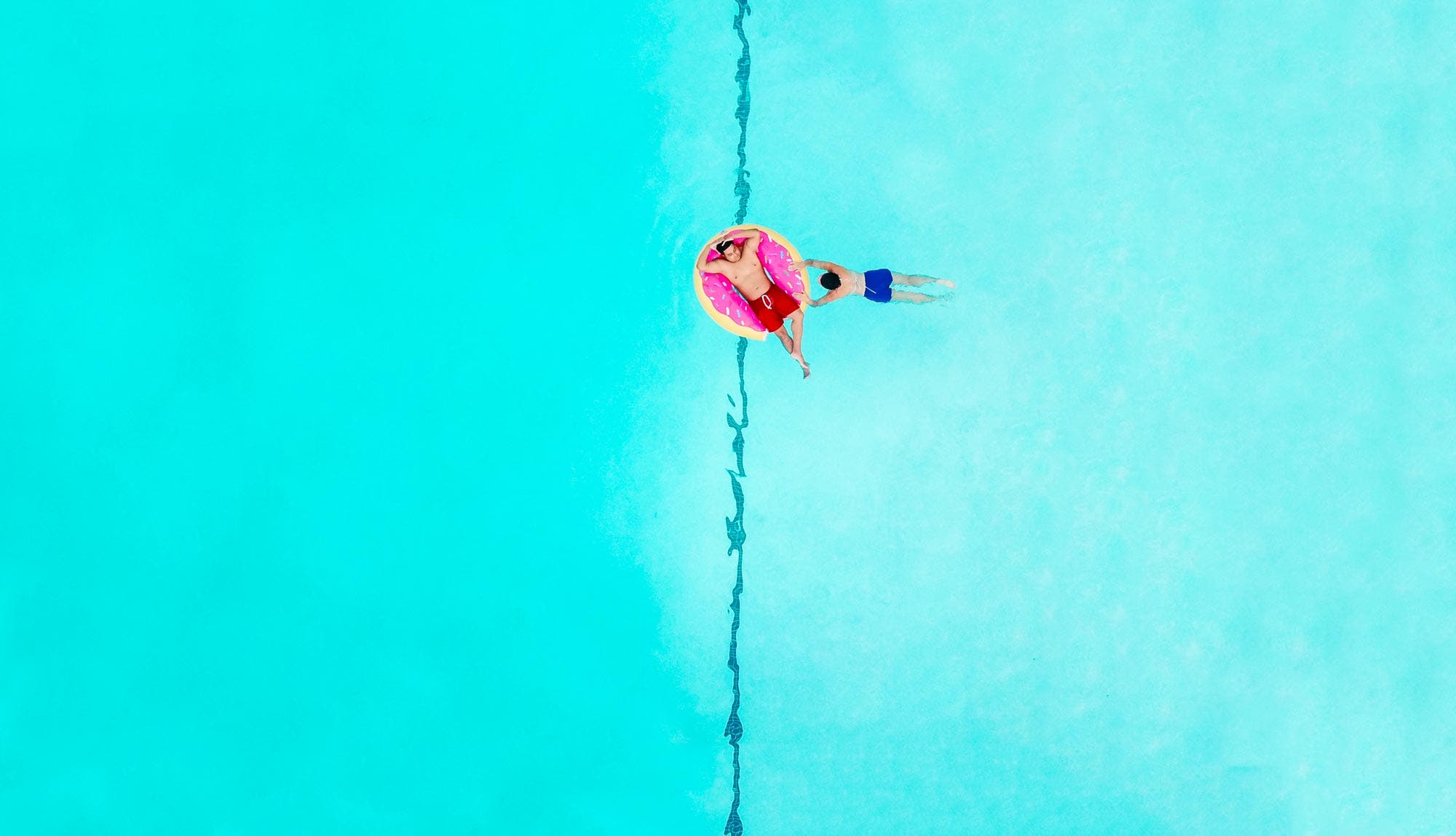 two men relaxing on donut pool floatie drone photography