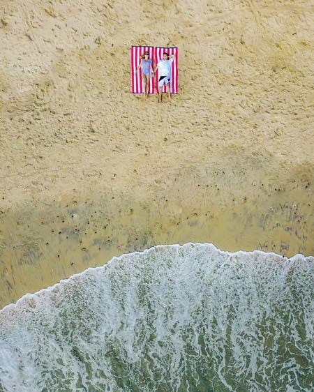 couple relaxing on beach drone photography