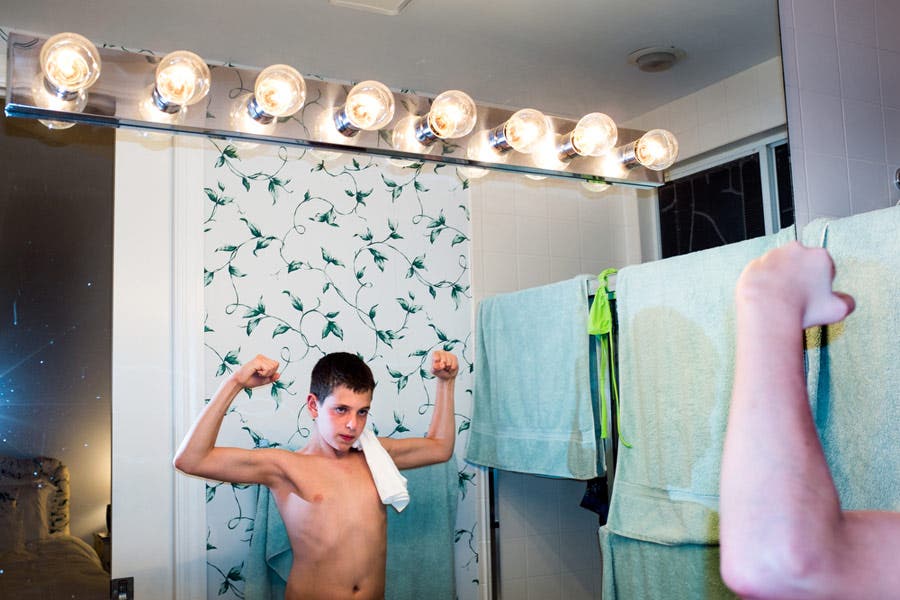 young boy looking flexing his muscles in the mirror