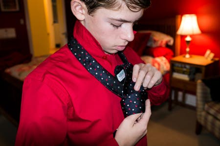 boy in a red shirt tying his necktie
