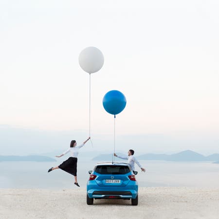 man and woman holding blue and white balloons with blue car