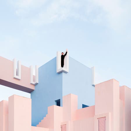 man waving from blue and pink architecture