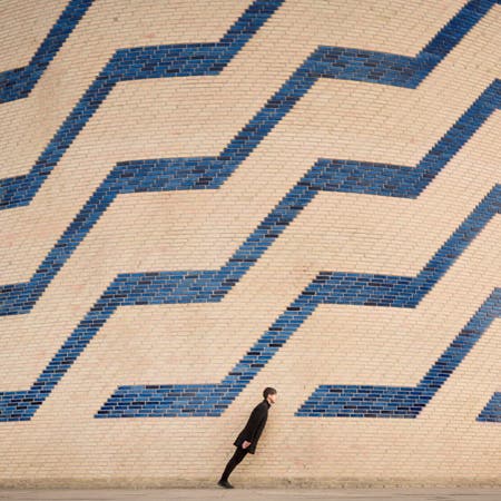 man leaning forward in front of wall with geometric pattern