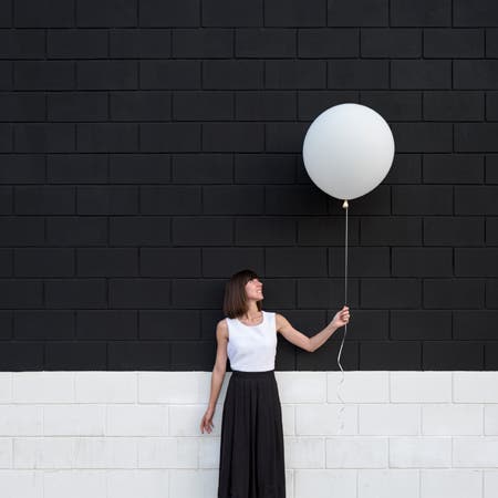 woman wearing black and white holding white balloon