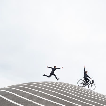 man chasing woman on a bicycle on top of a striped hill