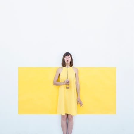 woman in a yellow dress standing in front of yellow wall