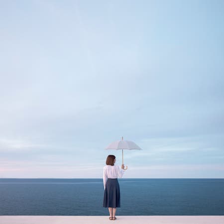 woman holding umbrella in front of ocean and sky