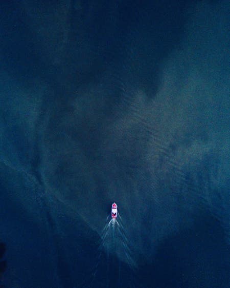 pink yacht in dark blue water drone photography