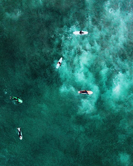 surfers in greenish blue water drone photography
