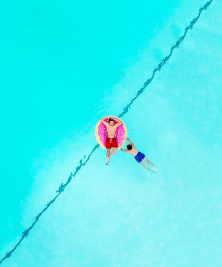 two men relaxing in pool drone photography