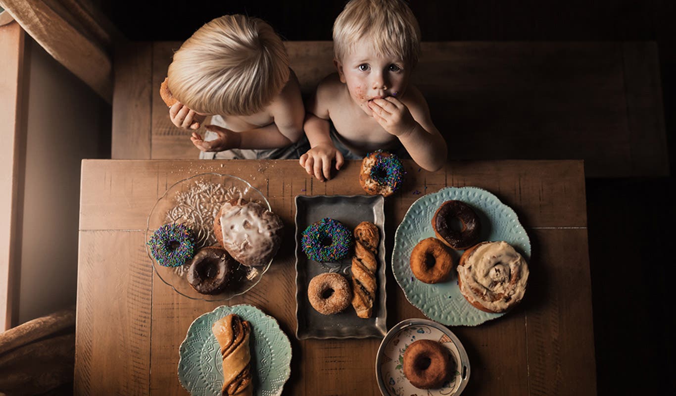 two young boys eating donuts at the table