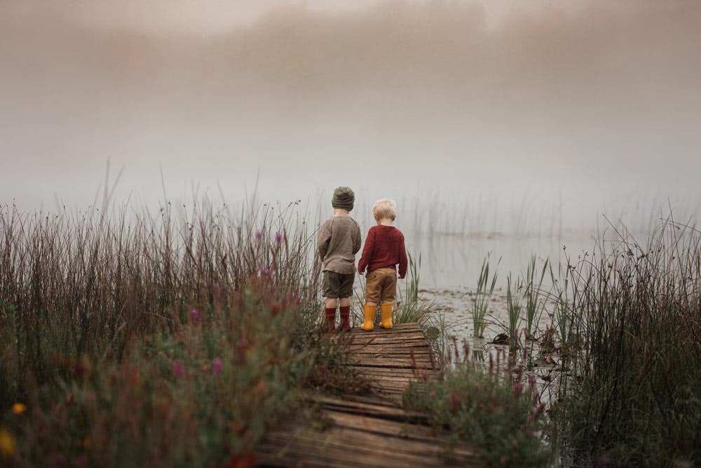 two young boys standing on the dock on a foggy day