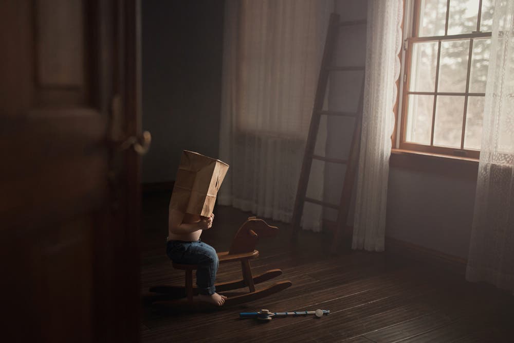 young boy on a rocking horse with a paper bag over his head