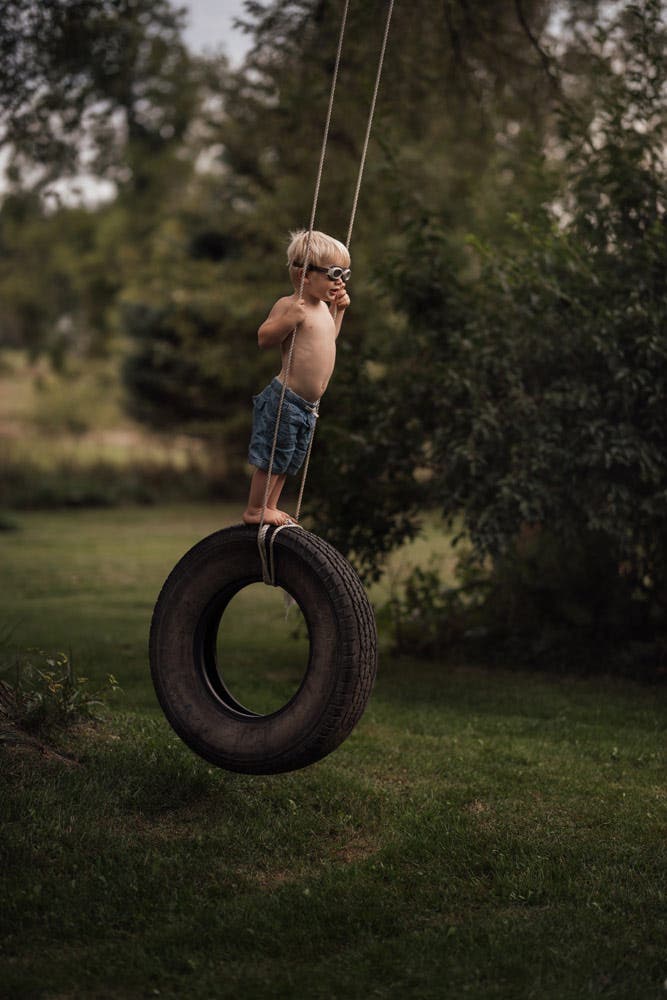 young boy swinging on a rubber tire