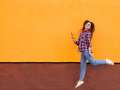 Cheerful girl mid jump against colored wall