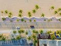 drone photography of beach boardwalk, cars, and palm trees