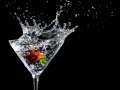 Fruit splashing into water in martini glass