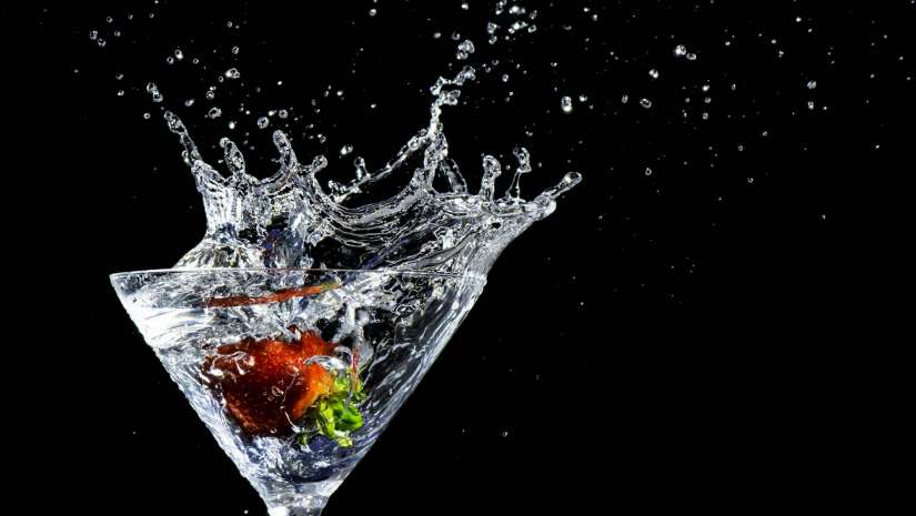 Fruit splashing into water in martini glass