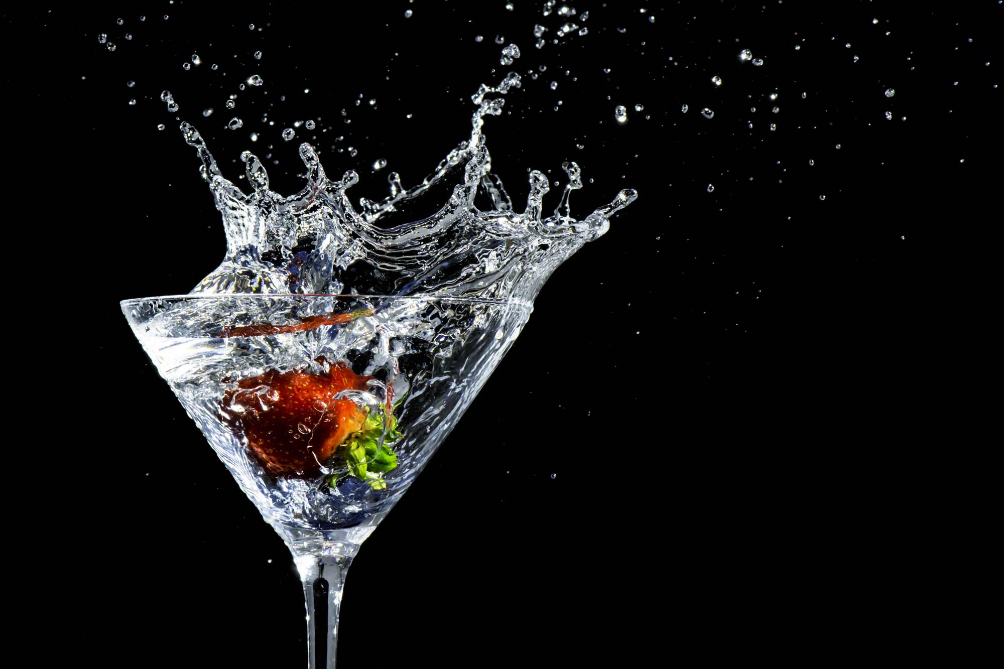 Fruit splashing into water in martini glass