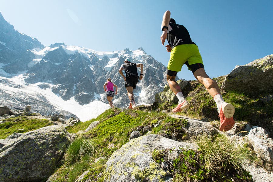 runners hiking up a rocky mountain path