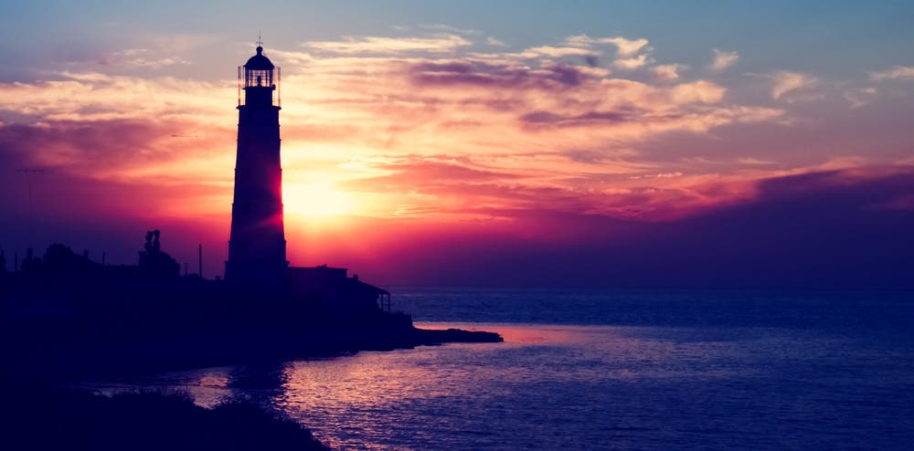 lighthouse by the sea during sunset