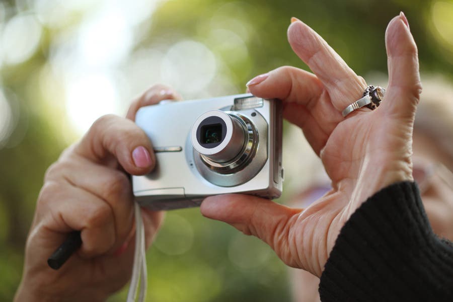 woman holding a point-and-shoot camera for street photography