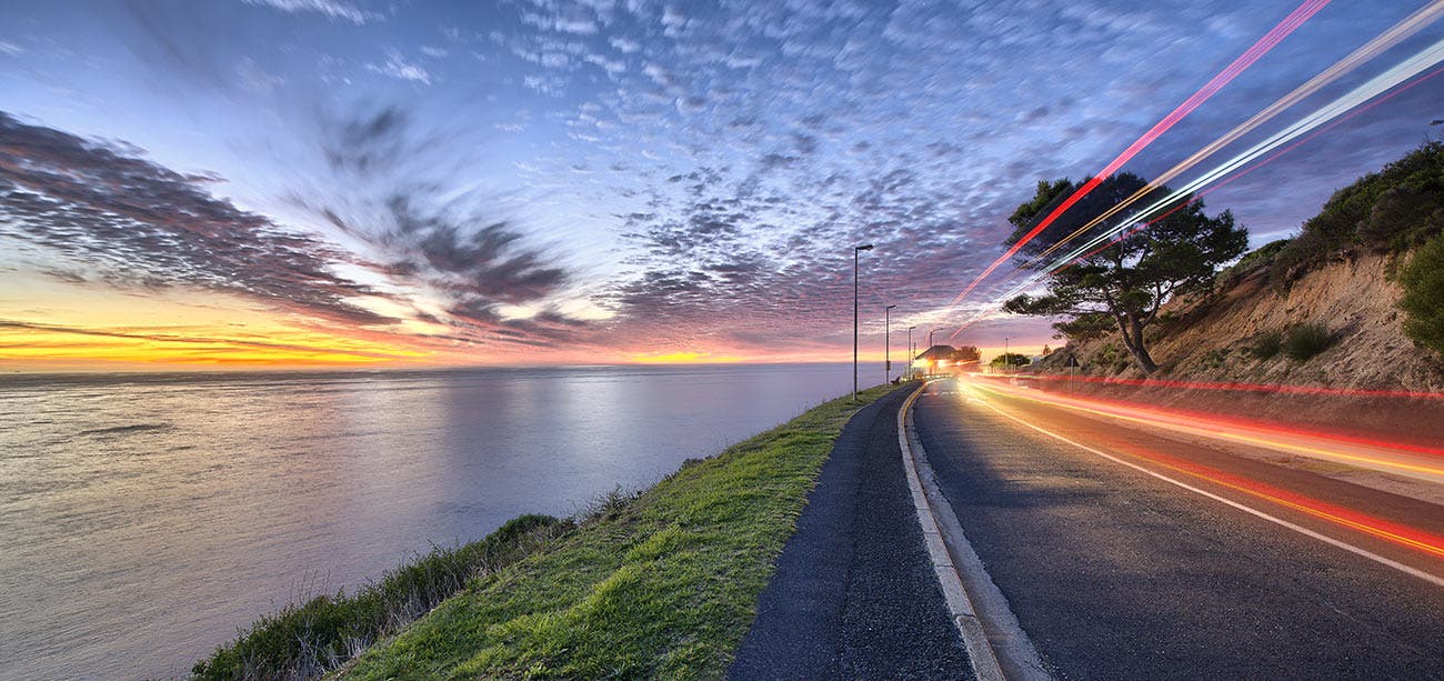 Time Lapse shot of water, clouds, and car lights