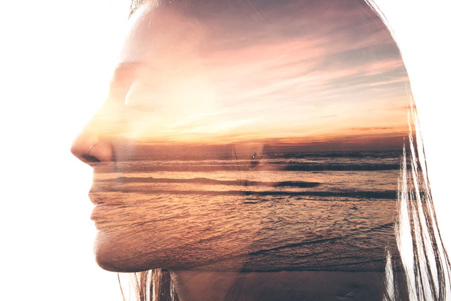 Double exposure of woman and sunset by the beach