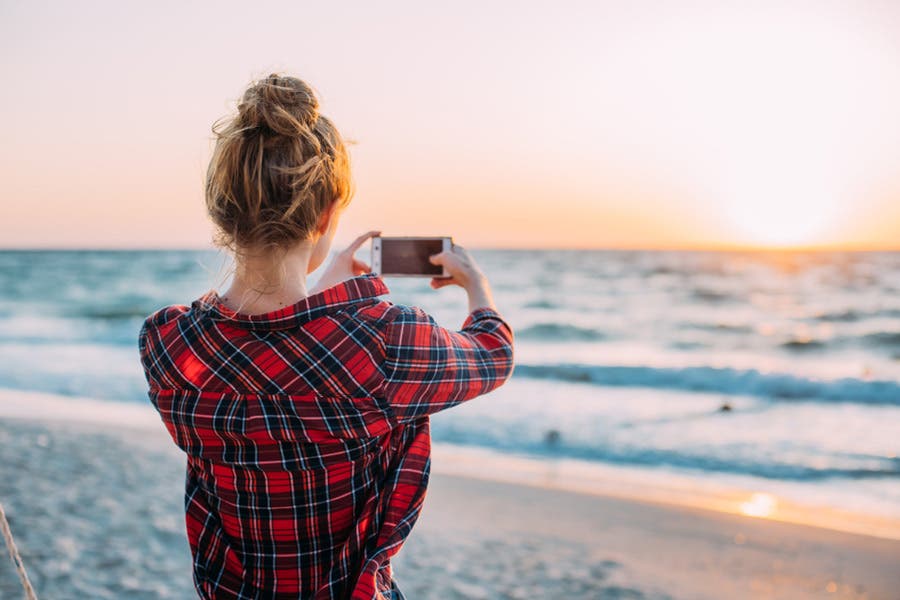 person taking a photo of the horizon on the beach