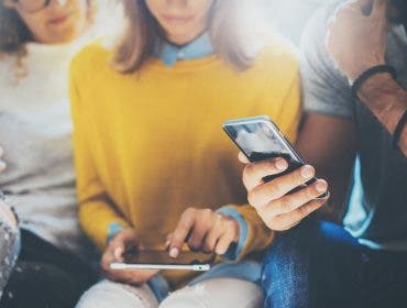 two women and one man looking at their smartphones