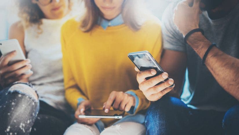 two women and one man looking at their smartphones