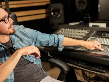 Music producer behind recording studio booth